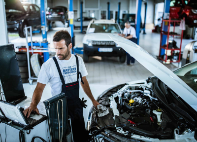 Mechanic standing next to open car hood